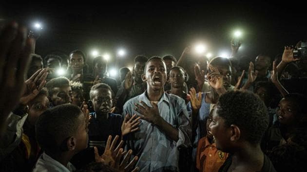 People chant slogans including “revolution” and “civil” as a young man recites a poem, illuminated by mobile phones, before the opposition’s direct dialogue with people in Khartoum, Sudan. (Yasuyoshi Chiba / AFP)