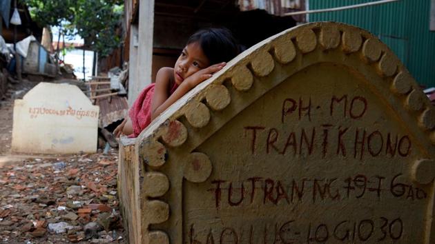 A girl lying on a grave in Phnom Penh. Graveyards may traditionally be the eternal resting place for the dead, but one cemetery in Phnom Penh is increasingly becoming a place to stay for the living as land disputes plague the nation’s poor. (Tang Chhin Sothy / AFP)