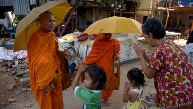 A woman and children greet monks as they stand in front of graves. Buddhist-majority Cambodia typically cremate their dead but the cemetery’s long-term occupants are mostly ethnic Vietnamese, who believe in burials. While the dead may not care, their relatives do, and the growing community has even prompted some to start unearthing their loved ones and interning them elsewhere. (Tang Chhin Sothy / AFP)