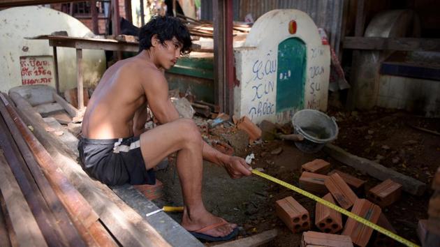 A man prepares the foundation to build a house above graves. Nearby, Am Sokha looked on as a neighbour laid the foundations for a new house next to several graves. He admitted to sometimes eating the food left as offerings to the dead. (Tang Chhin Sothy / AFP)