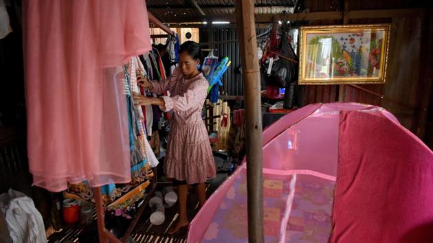 A woman arranges clothes inside her home in front of a grave. When Peanh Moeun first moved in 19 years ago after having to leave a relative’s house, there were more than 300 graves. Today, there are about 110 remaining, she said. With 500 active residents, there are more living than dead. (Tang Chhin Sothy / AFP)