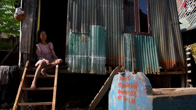 A woman sitting on the steps of her home next to a grave. Some came from a community whose riverside homes collapsed into the Bassac river, while others were evicted from nearby land to make way for a new market. They say the cemetery is the best option for them. Views across the river on Diamond Island show a vision of upmarket living with names such as Elite Town. (Tang Chhin Sothy / AFP)