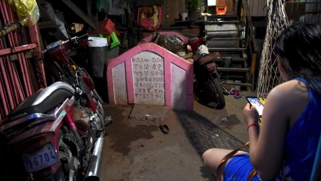 A woman looks at her smartphone beside a grave inside her home. “We are chasing the ghosts away,” said the 62-year-old, who used to be homeless but now wishes to stay in Smor San “for life”. “Living here is safe, close to markets, and we have electricity and water,” he said. (Tang Chhin Sothy / AFP)