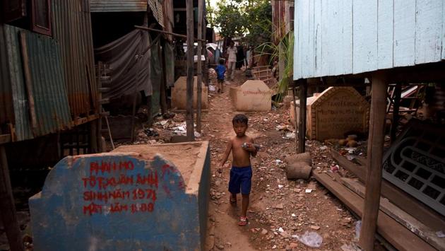 A boy walks past graves. But Am Sokha rubbished rumours of hauntings in the cemetery, which comes alive as night falls as villagers drink beer and children tumble around the tombs. He added: “It’s just said to scare people, but being scared is nothing compared to having no place to live.” (Tang Chhin Sothy / AFP)