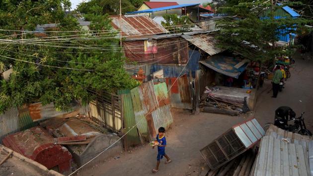 A boy walks past graves in Phnom Penh. Ma Nith’s family is one of roughly 130 residing in make-shift stilt houses and corrugated metal huts in between the colourful tombs of Smor San. Many residents erected their homes in the 1990s but there has been a steady increase since then. (Tang Chhin Sothy / AFP)