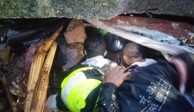A woman and a child were trapped under the debris of the wall, which collapsed on hutments killing 13 people in Mumbai’s Malad East early on Tuesday(HT Photo)