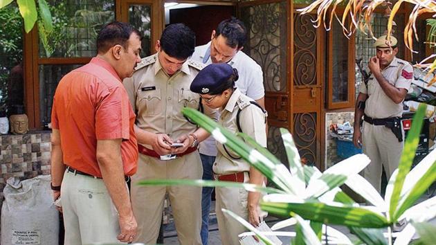 Police officials seen checking a mobile phone outside Shri Prakash Singh’s house, at Sector 49, in Gurugram.(Yogendra Kumar/Hindustan Times)