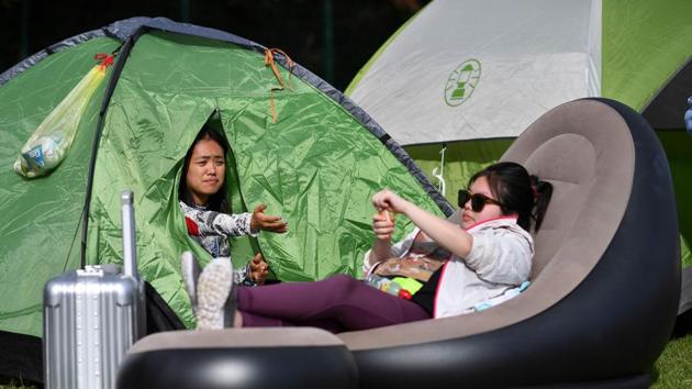 A couple of girls sit in their tents while they camp for a spot further up in the queue to buy tickets on the first day of the 2019 Wimbledon Championships tennis tournament. Wimbledon is one of few remaining major sporting events in the United Kingdom that still sells tickets on the day of play. (Ben Stansall / AFP)