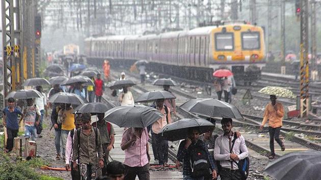 Commuters walk on track near thane railway station after train stop for mumbai Thane. ( Praful Gangurde/ HT Photo)