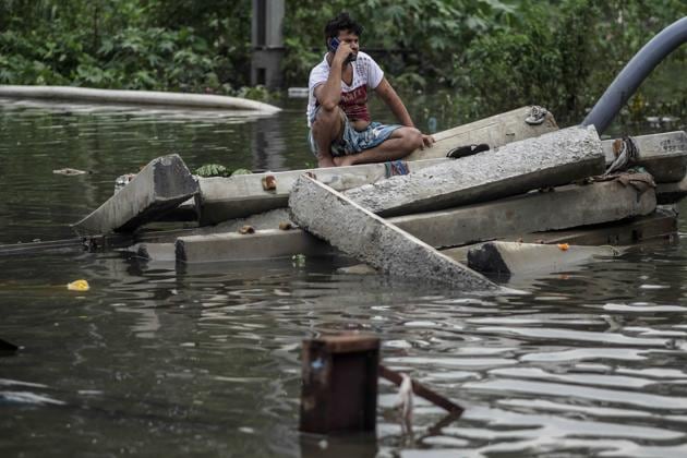 A man talks on a mobile phone while sitting on blocks of concrete surrounded by flood waters in the Tilak Nagar area of Mumbai, India, on Tuesday, July 2, 2019. The heaviest downpour since 2005 inundated Mumbai, delaying trains and planes and spurring the city administration to declare a holiday.(Bloomberg)