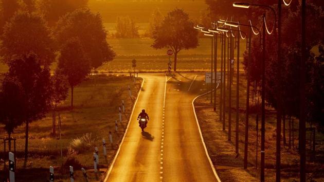 A man rides his bike on a land road as the sun rises in the outskirts of Frankfurt, Germany. (Michael Probst / AP) A man rides his bike on a land road as the sun rises in the outskirts of Frankfurt, Germany. (Michael Probst / AP)