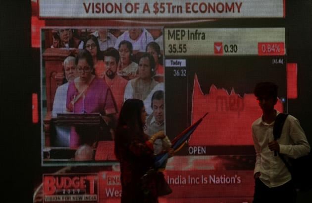 People walk as a telecast of India's Finance Minister Nirmala Sitharaman presenting the budget is displayed inside the Bombay Stock Exchange (BSE) building in Mumbai, July 5, 2019.(Reuters) People walk as a telecast of India's Finance Minister Nirmala Sitharaman presenting the budget is displayed inside the Bombay Stock Exchange (BSE) building in Mumbai, July 5, 2019.(Reuters)