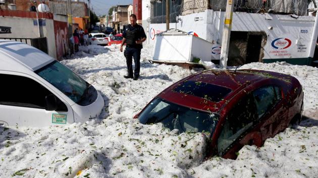 A policeman stands next to vehicles buried in hail in the eastern area of Guadalajara, Jalisco state, Mexico. The accumulation of freak hail in the streets of Guadalajara buried vehicles and damaged homes. (Ullises Ruiz / AFP) A policeman stands next to vehicles buried in hail in the eastern area of Guadalajara, Jalisco state, Mexico. The accumulation of freak hail in the streets of Guadalajara buried vehicles and damaged homes. (Ullises Ruiz / AFP)