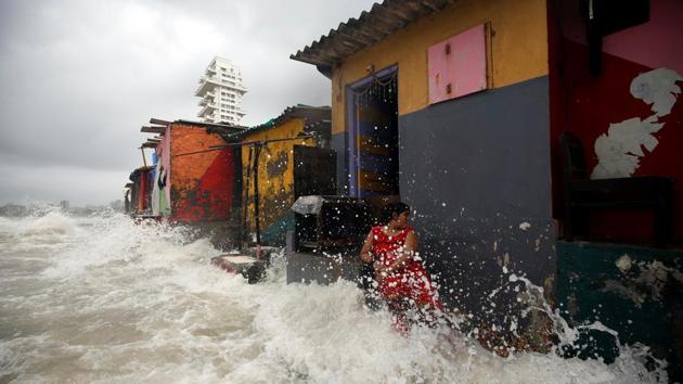 A woman gets drenched by waves outside her house along a seafront during high tide in Mumbai, Maharashtra. (Francis Mascarenhas / REUTERS)
