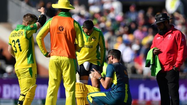 Australia's Usman Khawaja (C) receives medical attention during the 2019 Cricket World Cup group stage match between Australia and South Africa at Old Trafford in Manchester, northwest England, on July 6, 2019. (Photo by Paul ELLIS / AFP) / RESTRICTED TO EDITORIAL USE(AFP)