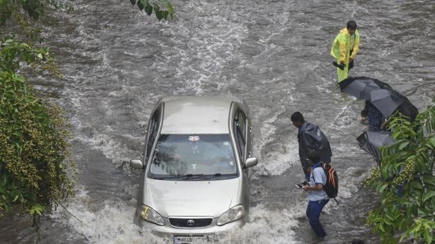 People walk along a flooded street after heavy rain showers at Sion on Monday.(HT Photo)