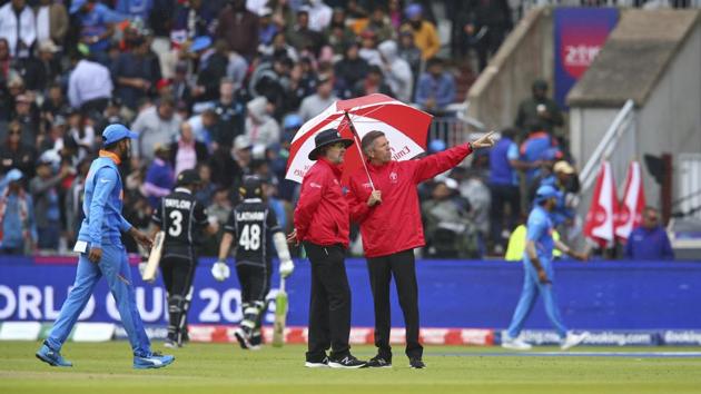 Umpires stand on the pitch with an umbrella as players leave the field. (AP) Umpires stand on the pitch with an umbrella as players leave the field. (AP)