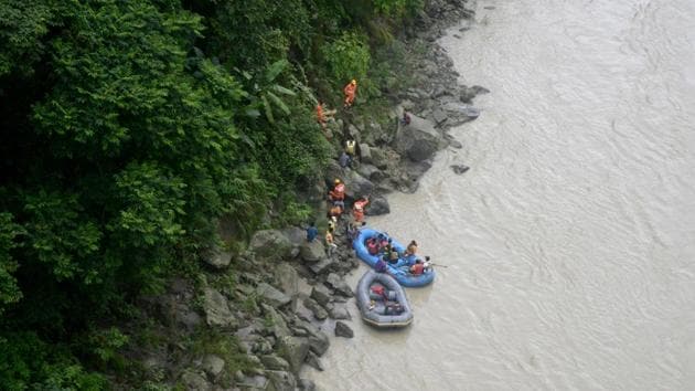 National Disaster Response Force personnel search along the banks of the Teesta river after a vehicle with three men on board plunged into the river when driving along the National Highway 23 km from Siliguri on Wednesday. The SUV was on its way to Gangtok.(AFP)