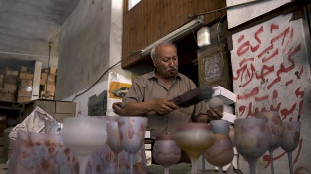 “We have been economically damaged. We are staying, but things are really difficult,” said Abed Abu Sido, one of Gaza’s last glassmakers, as he flipped through a glossy catalog of his products. At his quiet workshop, layers of dust covered the few remaining glass artifacts, requiring him to scrub them to reveal their colors. Cardboard boxes of unfinished products and materials were stacked floor-to-ceiling. (Khalil Hamra / AP)