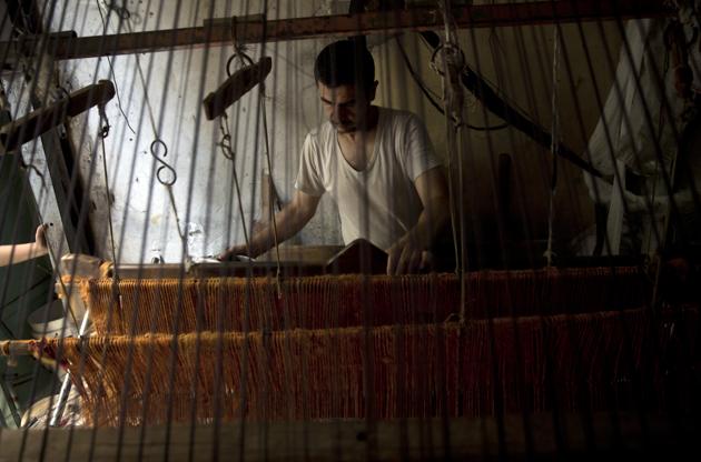Palestinian worker weaves carpets on a traditional wooden loom at a carpets factory in Gaza City. When Gazans think of better economic times, images of clay pottery, colourful glassware, bamboo furniture and ancient frame looms weaving bright rugs and mats all come to mind. While such professions have shrunk worldwide in the face of globalization and Chinese mass production, Gazan business owners say Israel’s 12-year blockade of the territory has accelerated the trend. (Khalil Hamra / AP)