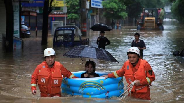 Rescue workers wade through flood waters as they evacuate a woman with an inflatable swimming pool on a street following heavy rainfall in Pingxiang, Jiangxi province, China. (REUTERS)