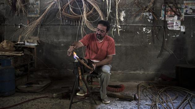 Palestinian Tarek Khalaf uses a flame to form bamboo at his family's workshop. For decades, these traditional crafts defined the economy of the coastal Palestinian enclave, employing thousands of people and exporting across the region. Today, the industries are almost non-existent.Under the blockade, Israel has greatly restricted exports and limited imports of raw materials. With unemployment over 50%, demand from the local market is weak. Israel blames the situation on Hamas, an armed group that opposes Israel’s existence. (Khalil Hamra / AP)