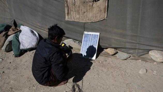 Manoj Mandal, 19, charges his mobile phone using a solar panel at his campsite. Migration for work is common in rural India. According to the non-government Aajeevika Bureau agency, millions work in hazardous conditions with little legal or social protection. (Xavier Galiana / AFP) Manoj Mandal, 19, charges his mobile phone using a solar panel at his campsite. Migration for work is common in rural India. According to the non-government Aajeevika Bureau agency, millions work in hazardous conditions with little legal or social protection. (Xavier Galiana / AFP)