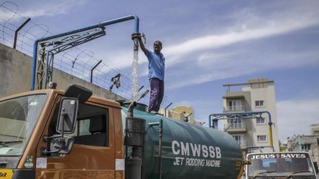 A water tank operator pours water from a pipe into a water tanker at a government-run filling station in Chennai. The water shortages risk further hurting the already struggling state-run health system. India spends only around 1% of GDP on healthcare, and aims to increase it to 2.5% by 2025. (Dhiraj Singh / Bloomberg)