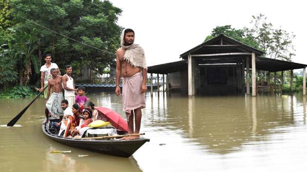 Villagers travel on a boat through flood waters in Murkata village of Morigoan district in Assam. Barpeta in lower Assam and Dhemaji in Upper Assam are among the worst affected.(BIJU BORO/AFP.)