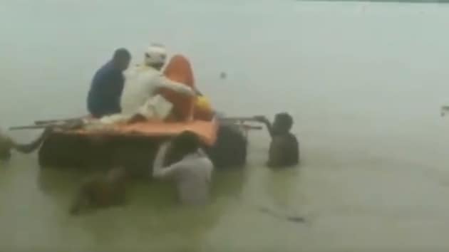 The newlyweds’ journey was halted due to a flooded road. They hopped on a makeshift boat to cross the road.(ANI Twitter (Screengrab))