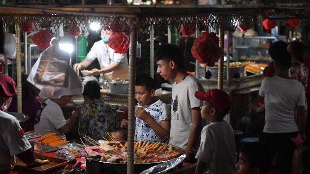 People at a night market Kashgar. Night markets too are more controlled. In Hotan, what used to be an outdoor night market is now inside a white tent, where red lanterns hang from the ceiling and uniform food stalls adorned with Chinese flags sell lamb skewers, but also sushi and seafood. (Greg Baker / AFP) People at a night market Kashgar. Night markets too are more controlled. In Hotan, what used to be an outdoor night market is now inside a white tent, where red lanterns hang from the ceiling and uniform food stalls adorned with Chinese flags sell lamb skewers, but also sushi and seafood. (Greg Baker / AFP)