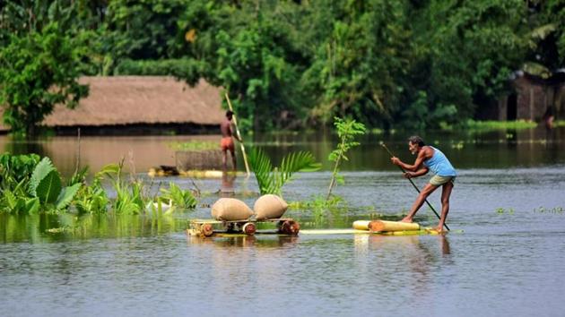 A man uses a makeshift raft to move his paddy to a safer place in a flooded area in Assam’s Morigaon district .(REUTERS)