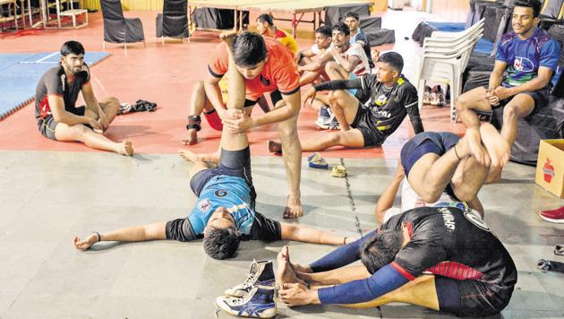 Chhawa Purandar players warm-up before practice at the Balewadi sports complex on Tuesday. Coaches are emphasising on the fitness of players ahead of the tournament given that not all players are used to the mat.(MILIND SAURKAR/HT)