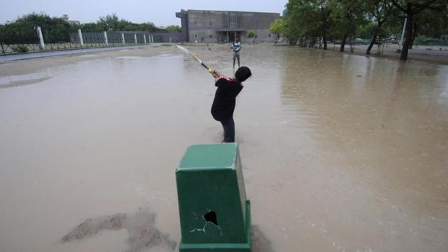 Children play cricket in a waterlogged ground during rain, at Noida stadium, in Noida, Uttar Pradesh. (Sunil Ghosh / HT Photo) 