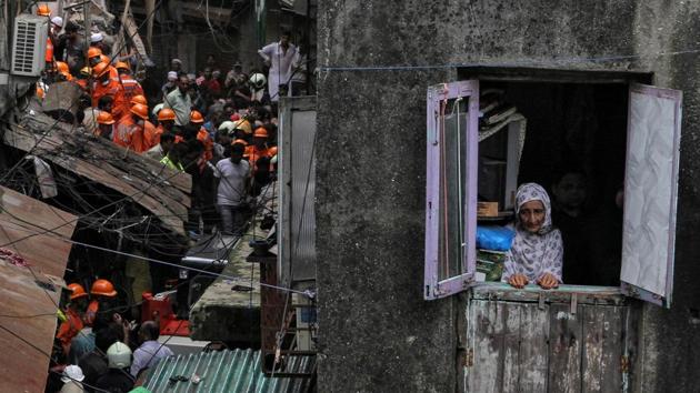 A resident looks out of her house as rescue workers search for survivors at the site of a collapsed building in Dongri, south Mumbai that left 14 dead and nine injured, in Maharashtra.  (Prashant Waydande / REUTERS) 