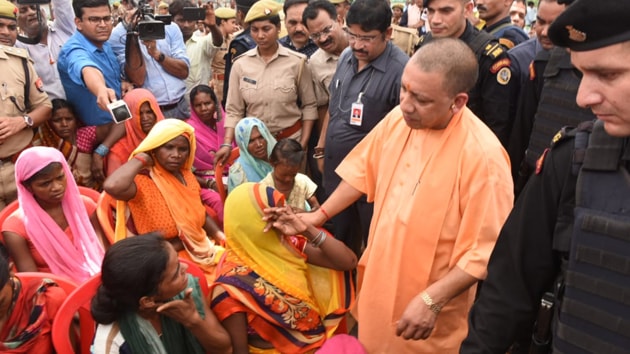 UP Chief Minister Yogi Adityanath with families of the 10 people killed in shootout in Umbha village in Sonbhadra.(HT Photo)