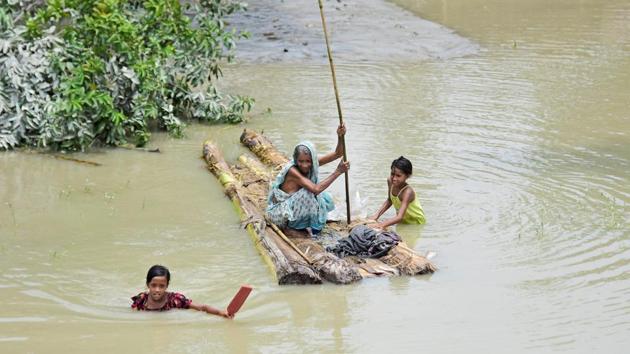 A woman rows a makeshift raft as girls wade through flood waters at the Laharighat village in Morigaon district, in the northeastern state of Assam, July 21, 2019.(REUTERS)