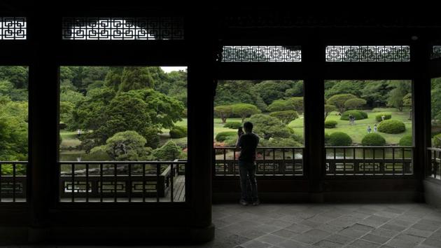 A tourist takes pictures from the Kyu Goryo-tei Pavilion in Shinjuku Gyoen national garden. Greater Tokyo has a population of more than 35 million — the world’s largest metropolitan area. (Jae C. Hong / AP)