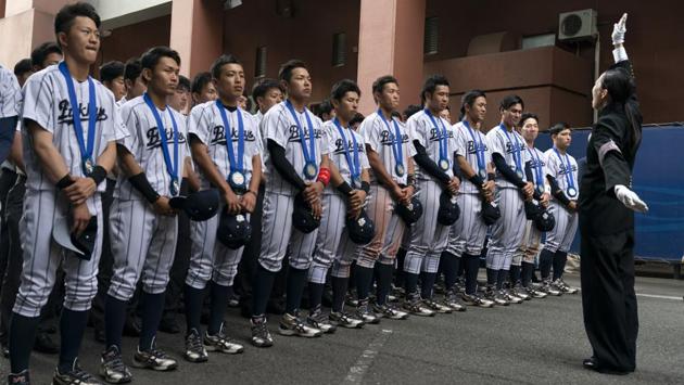 Bukkyo University cheerleading squad leader, Yamaguchi Karin (R) leads the school song in front of the school’s baseball players. Roy Tomizawa, a Japanese American who lives in Japan and published the most definitive book on Tokyo’s 1964 Olympics, said he applied for 16 tickets and got zero in the June lottery. (Jae C. Hong / AP)