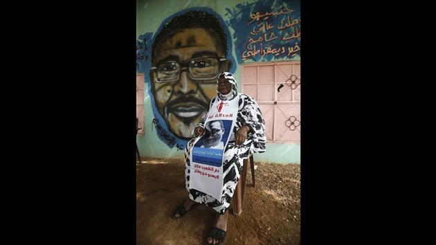 Maiyssa Omar, the mother of Walid Abdelrahim sits in front of the mural painting of her son, ornating the family home. “The painting keeps him alive,” she said, her voice choking as she talked of her son, who was killed during a three-day nationwide civil disobedience campaign in June. (Ashraf Shazly / AFP)