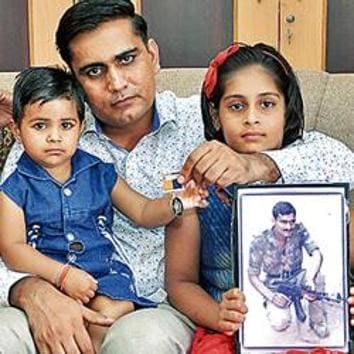 Kamla Devi (left), her older son, Devender Lamba, and granddaughters with a photo of her slain husband.(HT Photo)