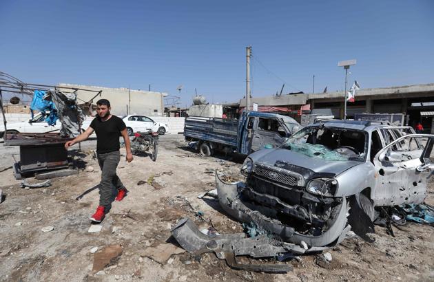 A Syrian walks past damaged cars following a reported air strike on a market in the town of Saraqeb in the northwestern province of Idlib on July 26, 2019.(AFP)