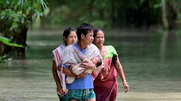 A man carries his new born baby as he and his family members wade through a flooded area to reach a relief camp at a village in Barpeta district of Assam, July 25, 2019.(REUTERS) A man carries his new born baby as he and his family members wade through a flooded area to reach a relief camp at a village in Barpeta district of Assam, July 25, 2019.(REUTERS)