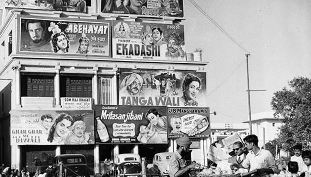 A man buys fruit in front of a hoarding promoting several films in Delhi in 1950.(Photo Credit: Richard Harrington/Three Lions/Getty Images)