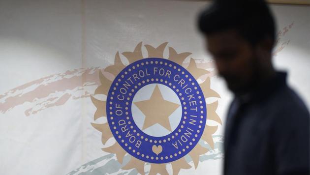 A man walks in front of the logo for the Board of Control for Cricket in India (BCCI) (AFP)