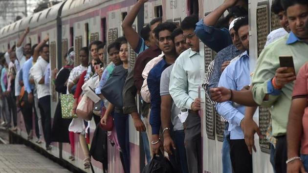 A crowded local passenger train approaches a platform in Mumbai. The railway ministry is reviewing the nearly dropped plan of introduction of semi-AC local trains, which will have a mix of general and AC coaches.(AFP)