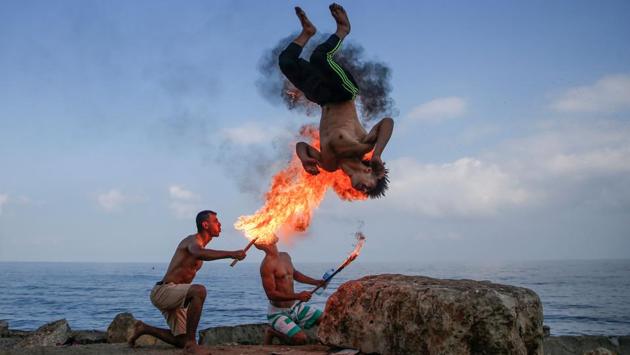 Men perform fire breathing on the beach as entertainment for children during the summer vacation in Gaza City, Palestine. (Mohamed Abed / AFP) Men perform fire breathing on the beach as entertainment for children during the summer vacation in Gaza City, Palestine. (Mohamed Abed / AFP)