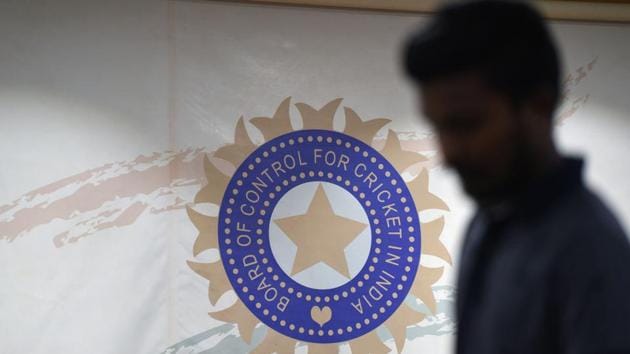 A man walks in front of the logo for the Board of Control for Cricket in India (BCCI)(AFP)