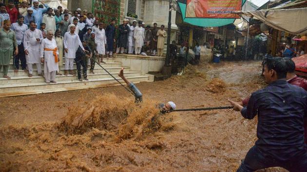 A man trips in rushing flood waters as he tries to hold onto a rope to help people to cross the street following heavy monsoon rains outside the Moinuddin Chishti Sufi shrine in Ajmer, Rajasthan. (Shaukat Ahmed / AFP) A man trips in rushing flood waters as he tries to hold onto a rope to help people to cross the street following heavy monsoon rains outside the Moinuddin Chishti Sufi shrine in Ajmer, Rajasthan. (Shaukat Ahmed / AFP)