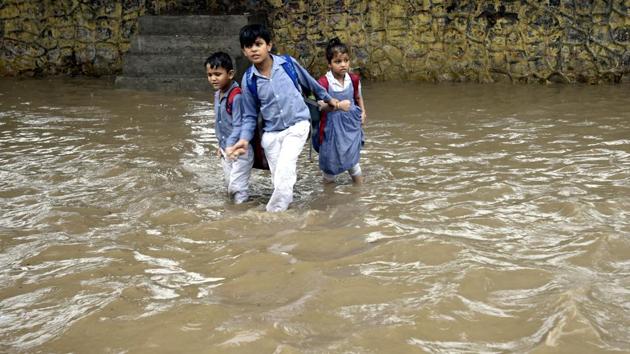 School students wade cautiously through a waterlogged road after heavy rain near Ramlila Ground in New Delhi.  (Raj K Raj / HT Photo) 